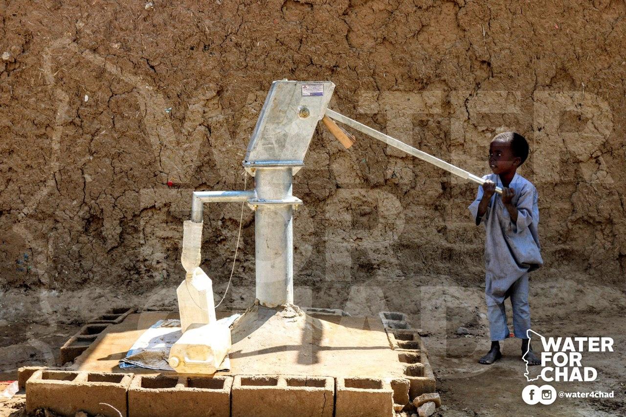 A boy pumps clean water from a new well