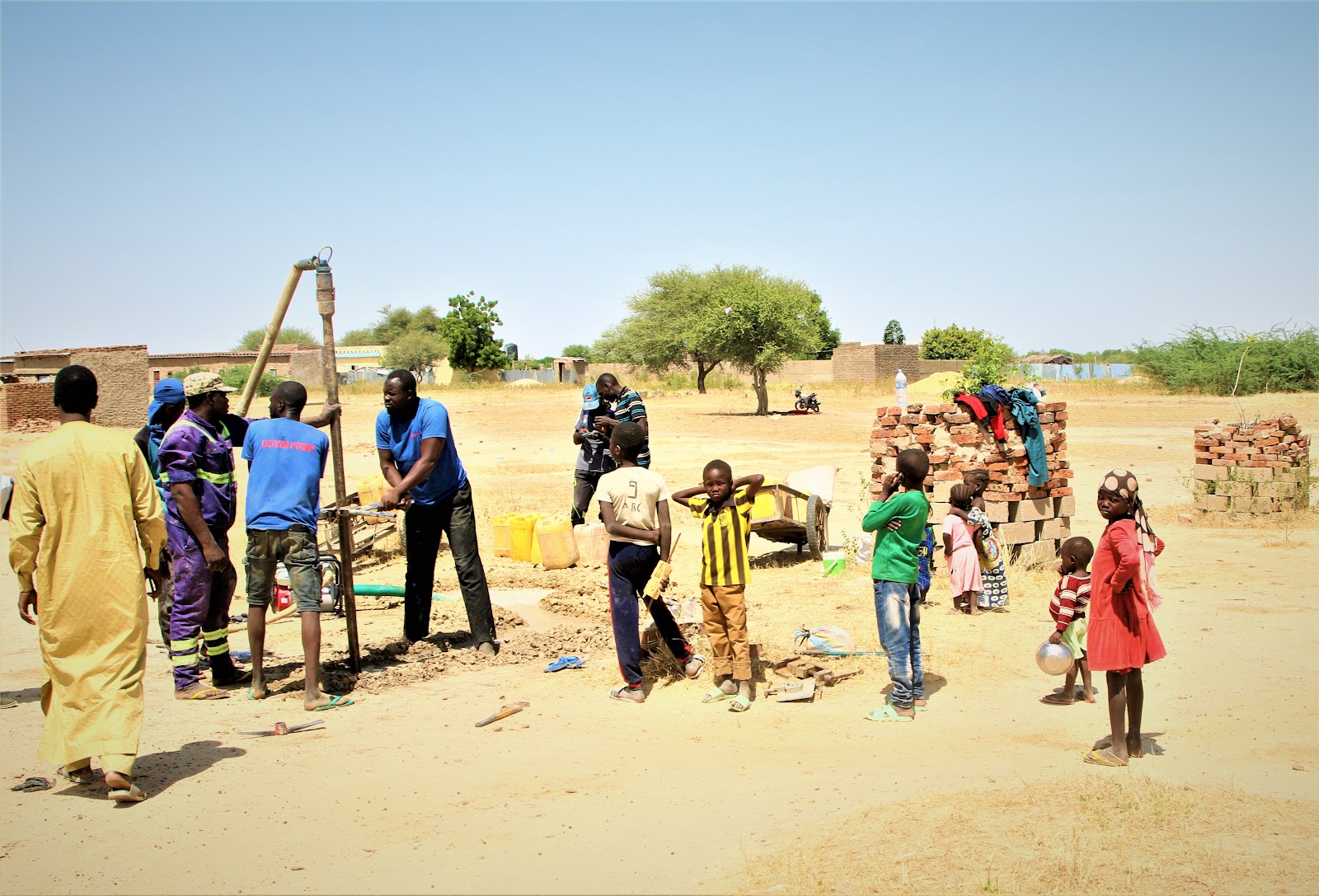 Water4Chad drilling team at work while community members and children watch
